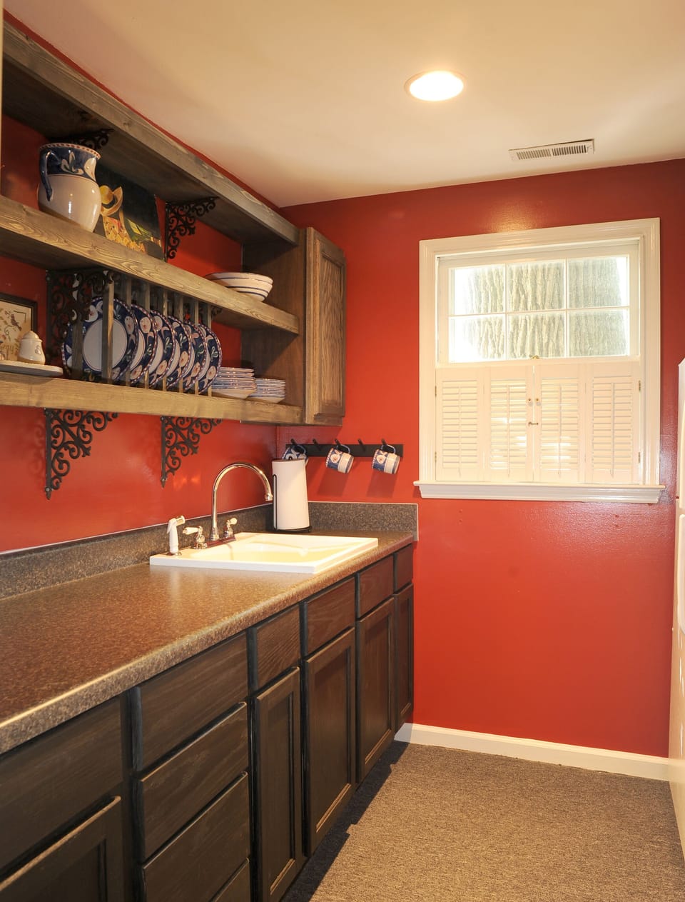 View of full kitchen with fridge, stove, oven, microwave and dishware. 