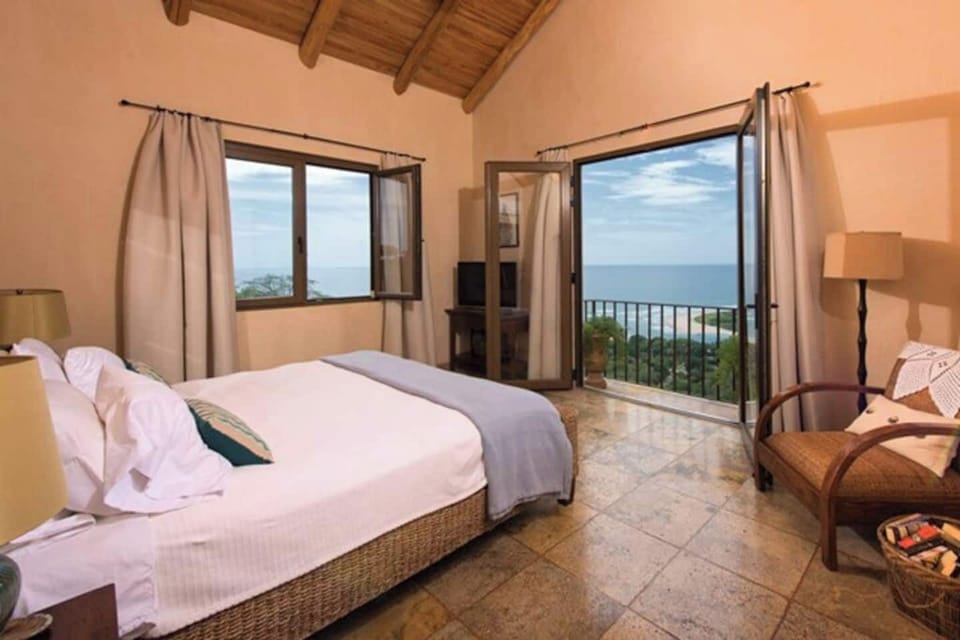 Spacious bedroom featuring a queen bed and a beautiful ocean view, combining comfort and style for the perfect Tamarindo vacation retreat.