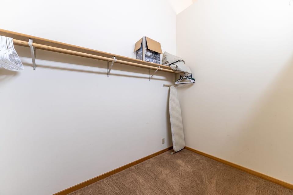 Your walk-in closet offers generous storage with sturdy shelving and hanging space, plus a convenient ironing board for keeping your wardrobe fresh.