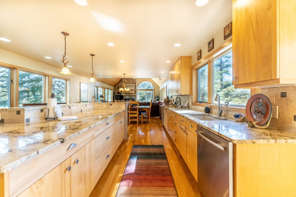 Your gourmet kitchen features granite counters, hardwood floors, and forest views through large windows.