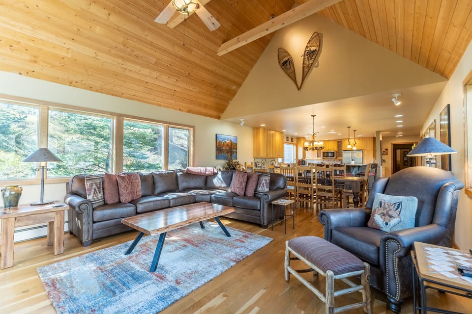 Unwind in this spacious open-concept living area where exposed beams and leather seating create your perfect mountain retreat sanctuary.