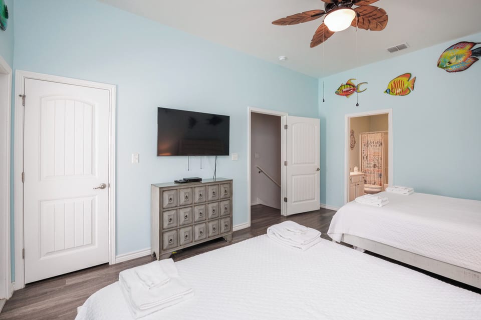 Your tropical-themed bedroom features twin beds, entertainment, and an ensuite bathroom with playful fish decor.
