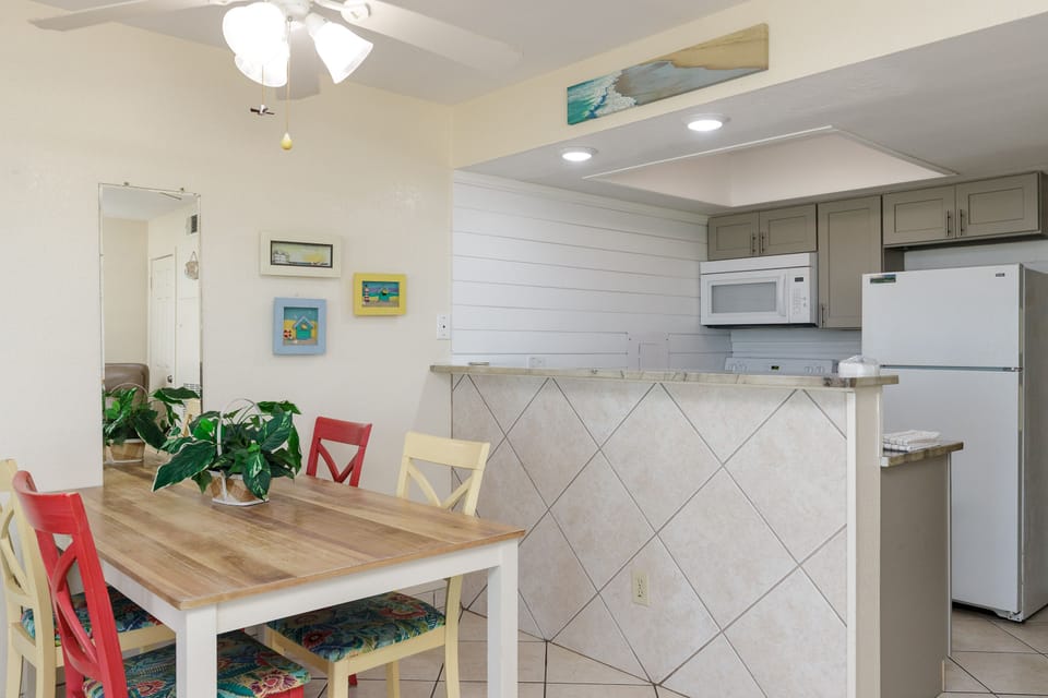 Enjoy relaxed meals at your charming dining table, perfectly positioned next to your fully equipped kitchen with modern appliances and coastal artwork.