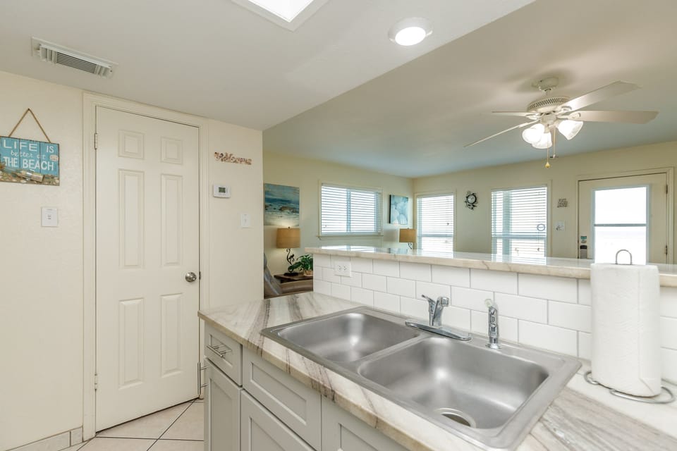 Your bright kitchen features marble countertops and a double sink, perfect for preparing meals with ocean-inspired decor surrounding you.