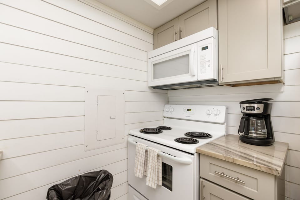Your fully equipped kitchen awaits with modern appliances and charming shiplap walls, perfect for brewing morning coffee or preparing meals.