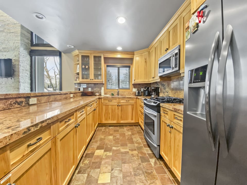 Spacious, fully equipped kitchen with stainless appliances, granite counters, and warm wood cabinetry—perfect for cooking après-ski meals and entertaining.