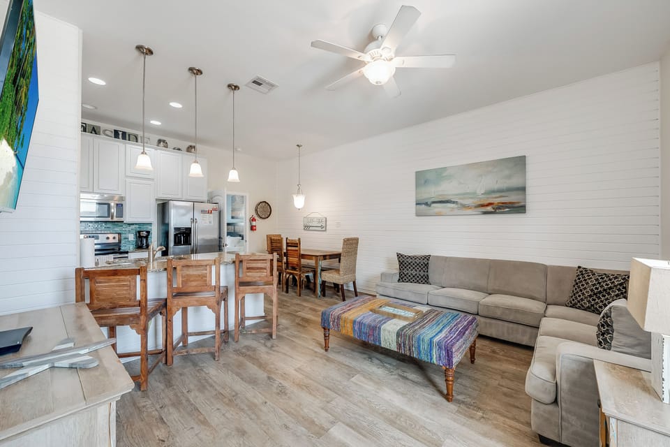 Your open-concept living space features comfortable seating, a fully equipped kitchen, and coastal-inspired touches that create the perfect home base.