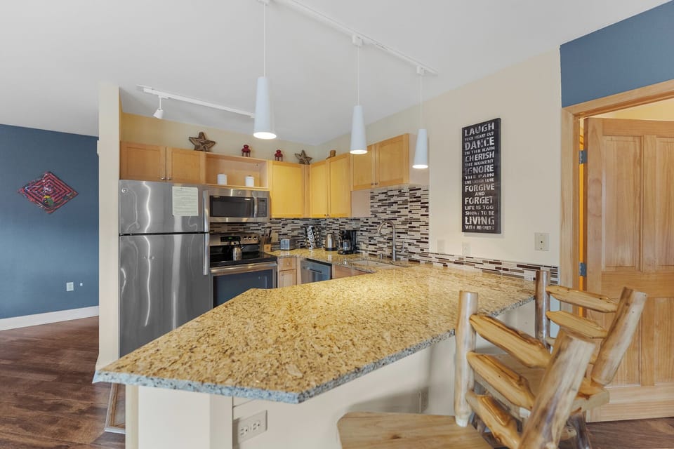 Your fully equipped kitchen awaits with granite counters, stainless appliances, and rustic bar seating perfect for morning coffee or casual meals.