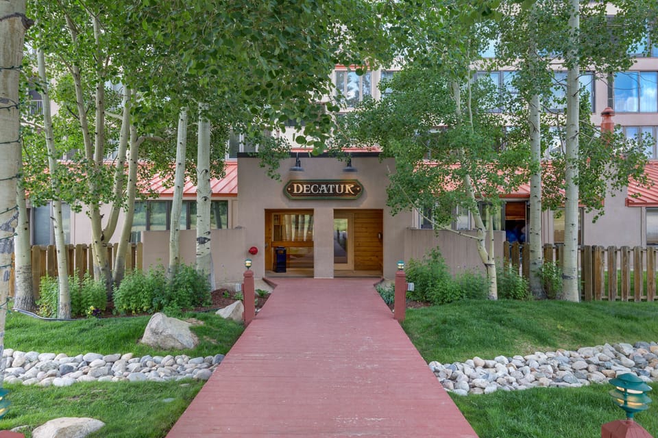 A welcoming property entrance with mature aspen trees and professional landscaping creates an inviting arrival experience.
