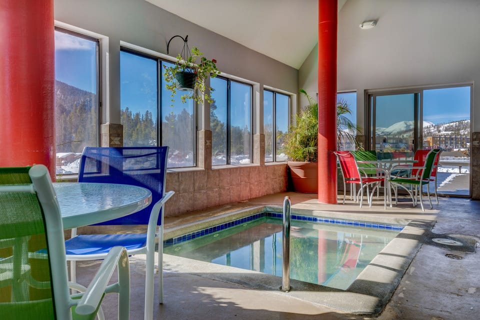 Unwind in your private indoor pool with stunning mountain views through floor-to-ceiling windows, surrounded by vibrant seating.