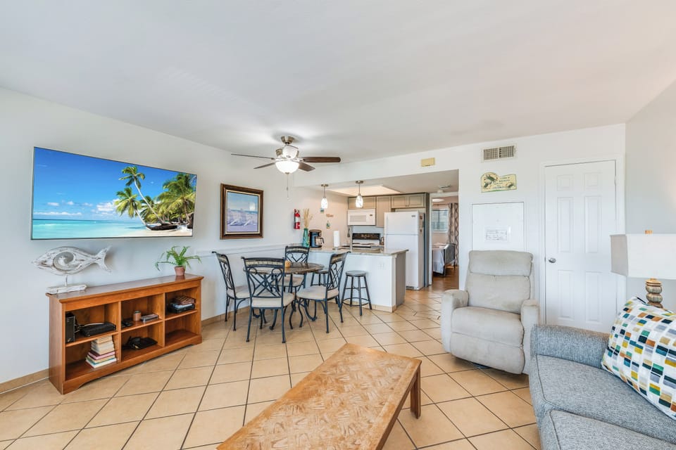 Relax in your bright, coastal-themed living space with comfortable seating, large TV, and open kitchen perfect for vacation meals together.
