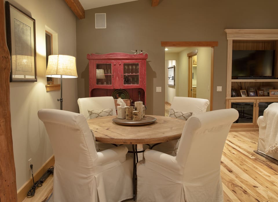 Gather around this charming rustic dining space where exposed beams and warm wood floors create the perfect ambiance for memorable meals with loved ones.