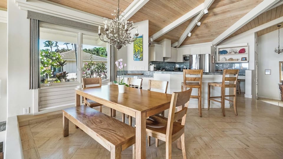 Gather around this inviting dining table where your group can enjoy meals together, bathed in natural light from large windows overlooking the garden. The open flow to the modern kitchen makes it easy to cook, serve, and create lasting memories.