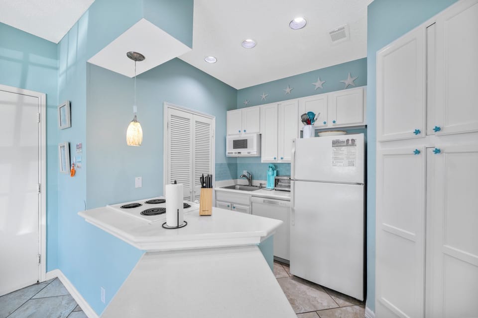 Your fully equipped kitchen features cheerful blue walls and white cabinetry, perfect for preparing meals during your stay.