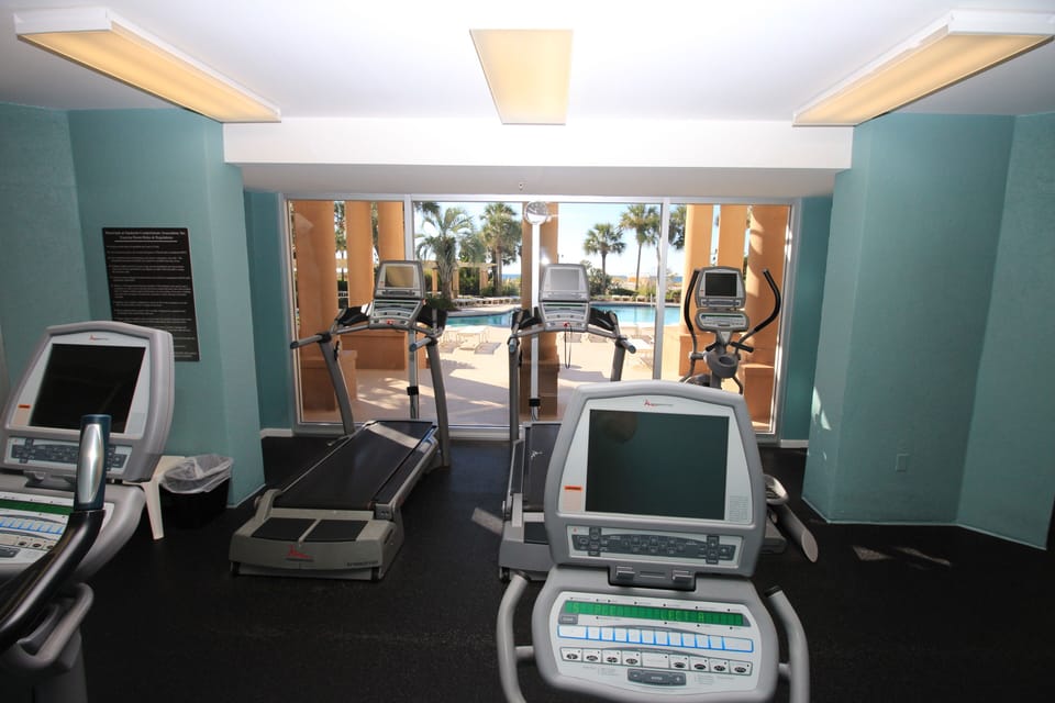 Fitness center overlooking pool and beach