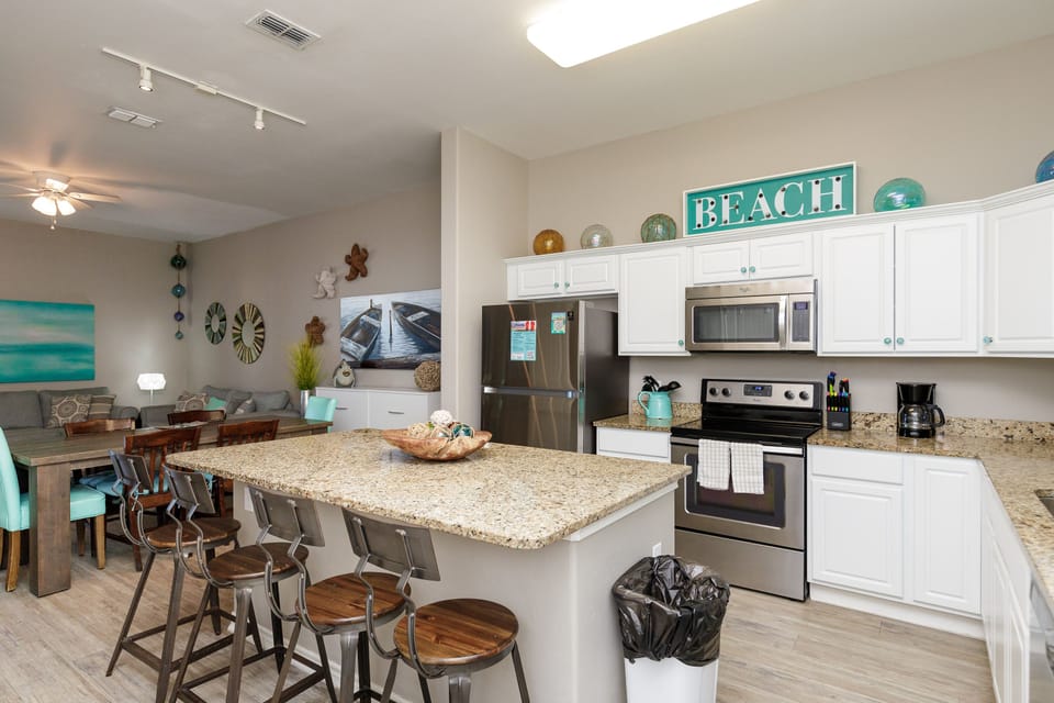 Your fully equipped kitchen flows seamlessly into the dining area, perfect for preparing beach-inspired meals together.
