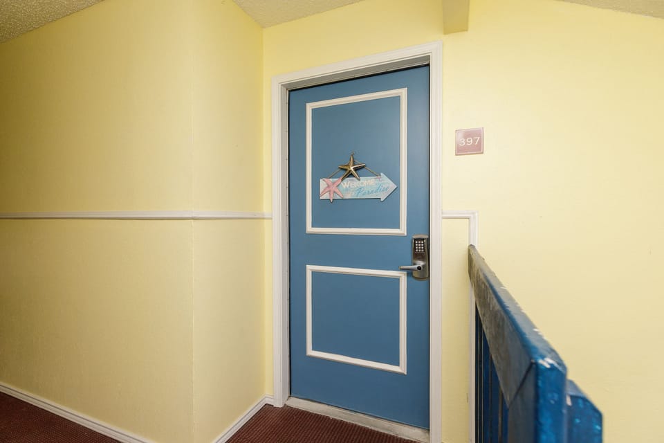 Your welcoming retreat awaits behind this cheerful blue door, where warm yellow hallways create an instantly inviting atmosphere for your stay.