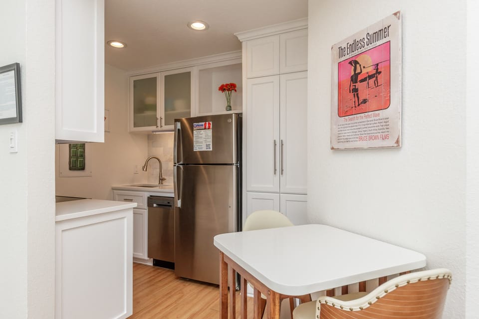 Your bright, fully-equipped kitchen awaits with stainless steel appliances, white cabinetry, and a cozy dining nook perfect for morning coffee.