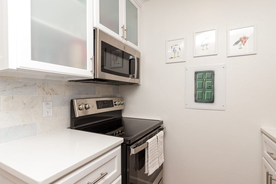 Your fully equipped kitchen features modern stainless steel appliances and elegant white cabinets, perfect for preparing meals during your stay.