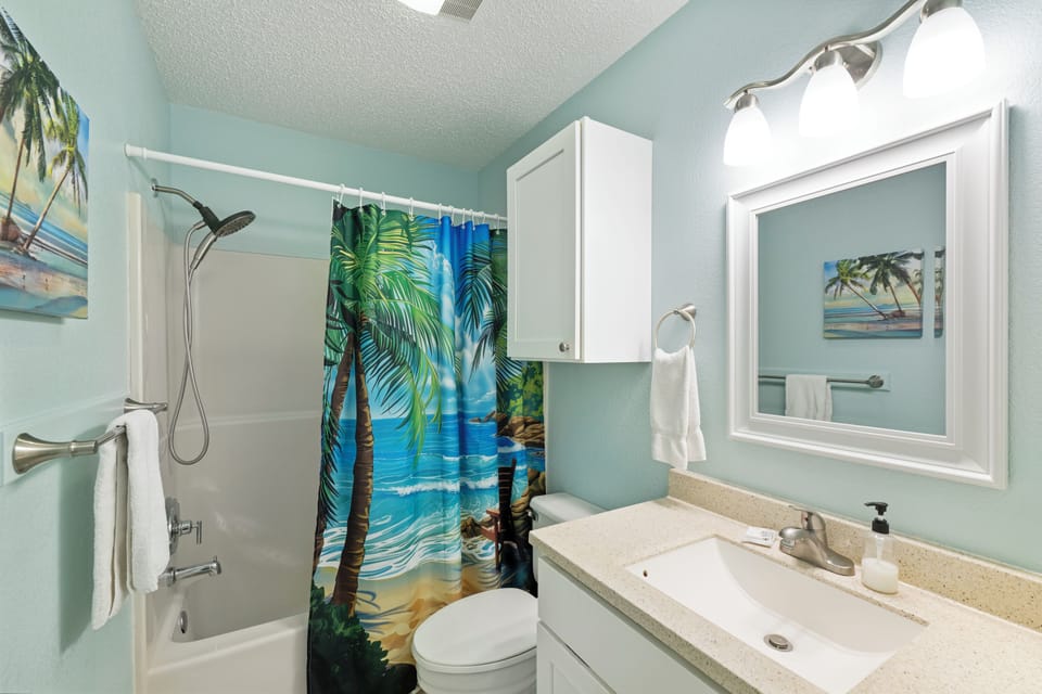 Refresh in your coastal-themed bathroom with tropical shower curtains and soothing blue walls that bring beachside tranquility to your daily routine.