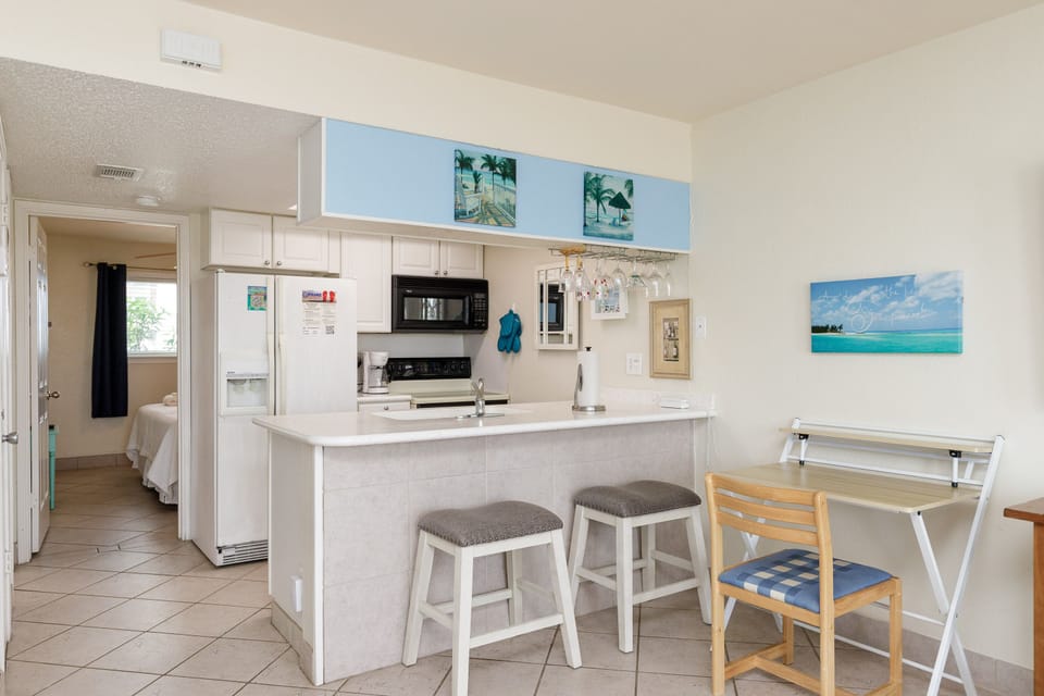 Your bright beach-themed kitchen features white cabinets, full appliances, and a breakfast bar where you'll start each morning.
