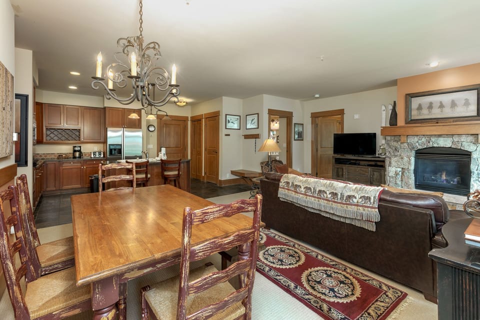 Relax in your elegant open-plan living space with stone fireplace, full kitchen, and dining for eight under a stunning chandelier.