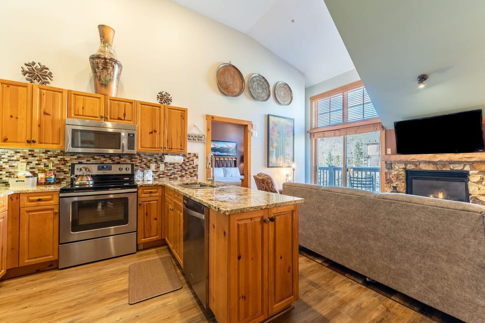 Your open-concept kitchen flows seamlessly into the living room, featuring granite counters, stainless appliances, and a cozy stone fireplace for perfect mountain evenings.