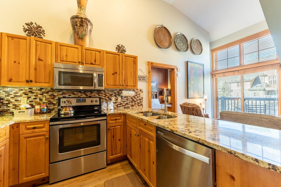 Your fully equipped kitchen features granite countertops, stainless appliances, and warm wood cabinetry—perfect for preparing meals while enjoying mountain views.