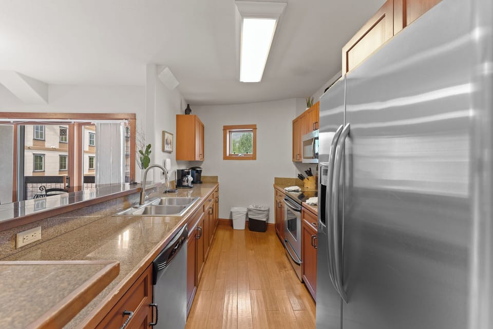 Your fully equipped kitchen features granite countertops, stainless steel appliances, and warm wood cabinets with natural light streaming through skylights.