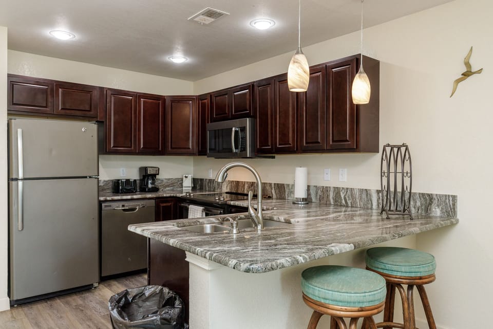 Your fully equipped kitchen features granite counters, stainless appliances, and a convenient breakfast bar for morning coffee.