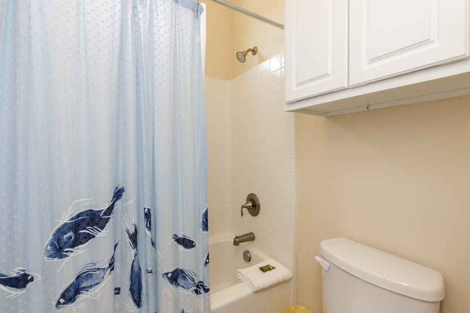 Refresh in your private bathroom with a charming ocean-themed shower curtain and ample storage above.