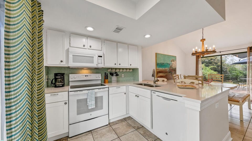 This kitchen has all the conveniences of home, including a stove, oven, microwave, dishwasher, and refrigerator. There is also a breakfast bar with stools.