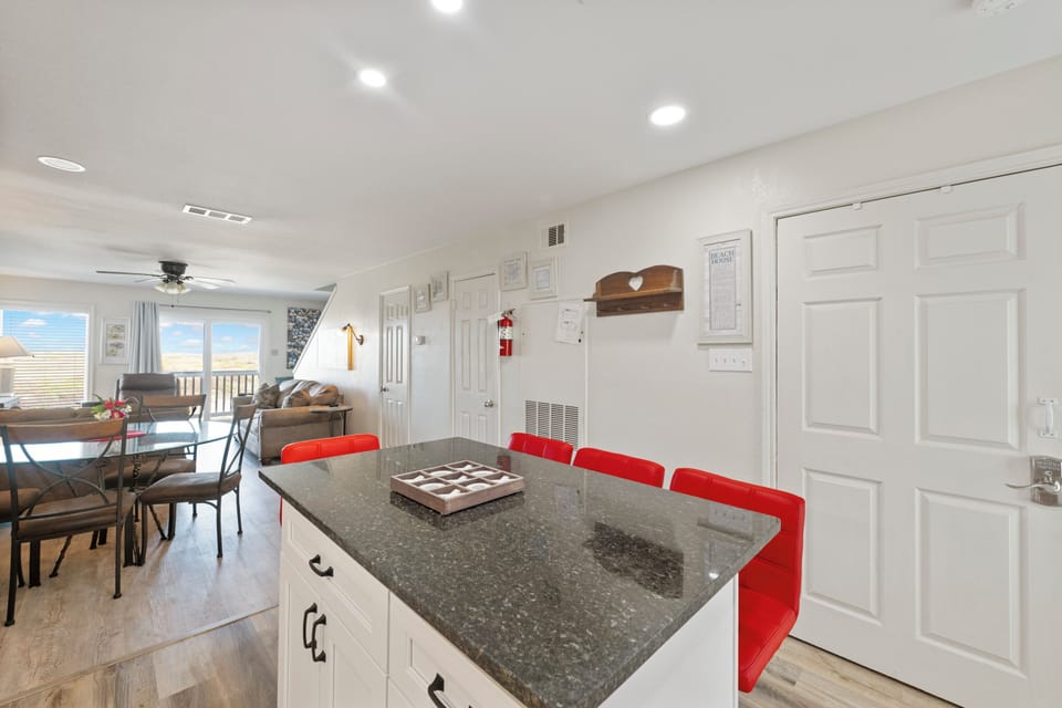 Your stylish kitchen island with bright red stools awaits morning coffee and meal prep, while windows frame scenic views.