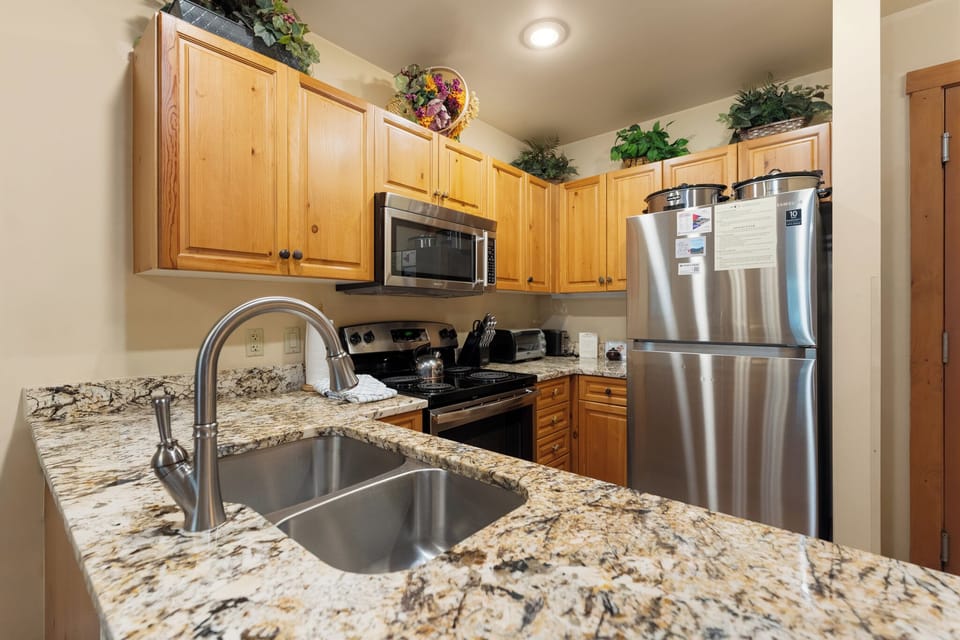 Your fully equipped kitchen features granite countertops, stainless steel appliances, and warm wood cabinets—perfect for preparing your favorite meals.