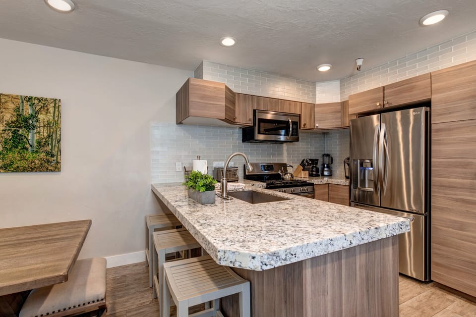 New kitchen with custom cabinets, stainless appliances, 6-burner gas stove, granite counters, and 3 bar seats