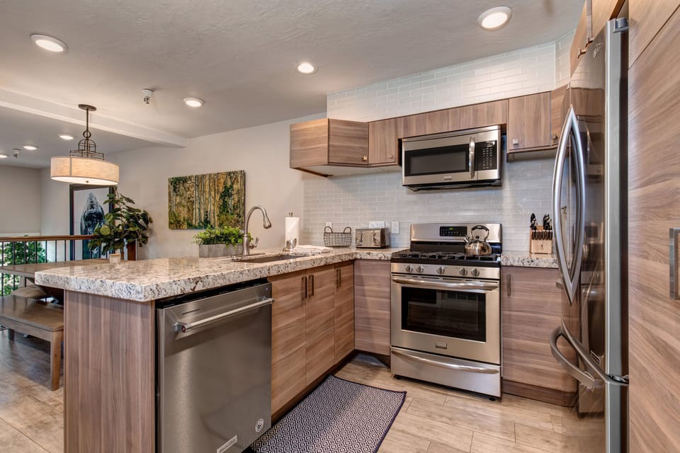 New kitchen with custom cabinets, stainless appliances, 6-burner gas stove, granite counters, and 3 bar seats