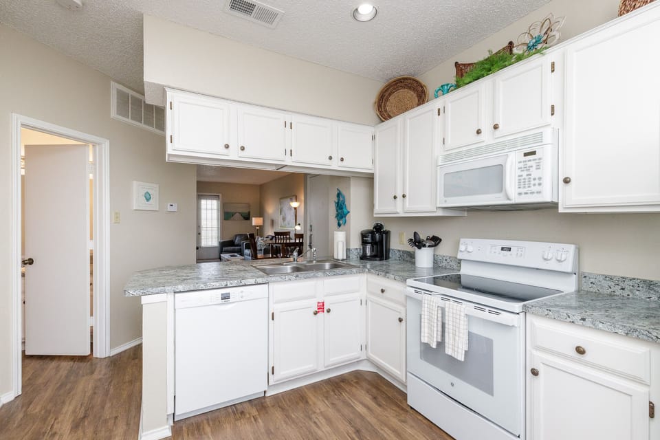 Your fully equipped kitchen awaits with granite counters, white appliances, and all the essentials for preparing your favorite meals together.