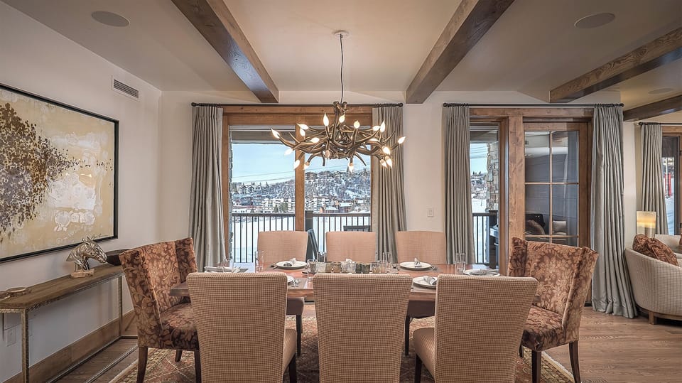 Gather around your elegant dining table where rustic beams meet refined comfort, creating the perfect setting for memorable meals with mountain views.