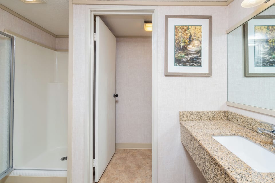 Step into your private bathroom featuring a spacious walk-in shower, granite countertops, and plenty of natural light to start your mornings right.