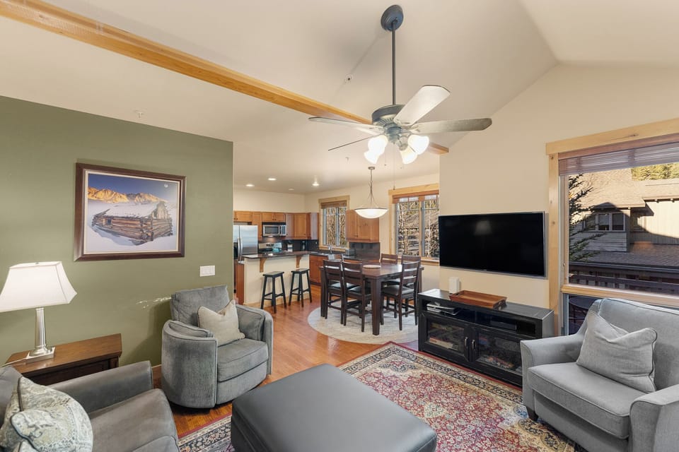 Relax in your open-concept living space featuring cozy gray seating, a warming fireplace, and seamless flow to the fully-equipped kitchen.