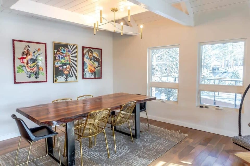 The stylish dining room located off the kitchen features a long table with seating for six, beautiful artwork, and a modern light fixture.