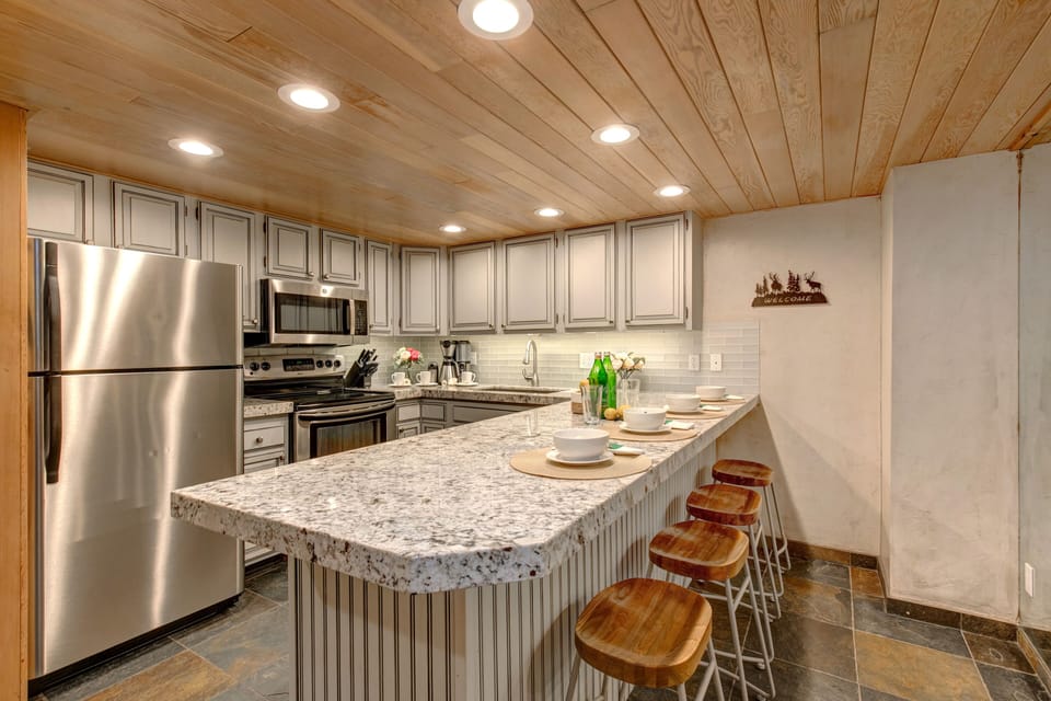 Fully equipped kitchen offering gorgeous quartz counters and stainless steel appliances, and bar with seating for up to four people