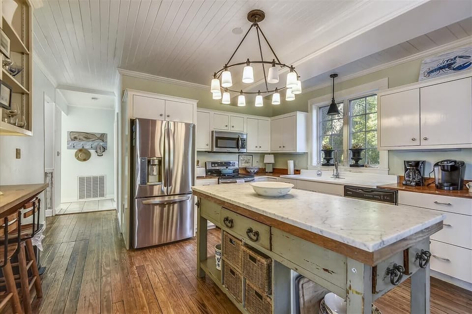 Main level kitchen - This roomy main-floor kitchen mixes old-Tybee charm with today’s comforts. The marble center island and eye-catching lighting steal the show.