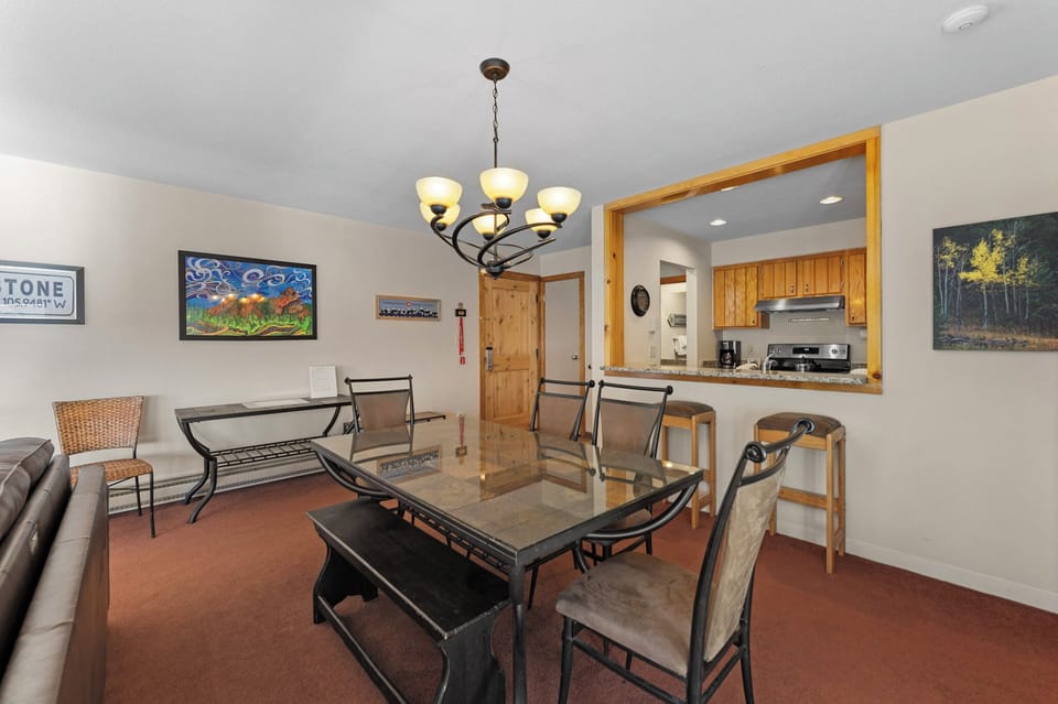 Your open dining area flows seamlessly into the kitchen, perfect for gathering around the elegant glass table under warm chandelier light.