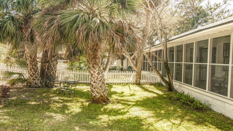 View of home exterior and yard - The wraparound screened porch offers breezy Tybee charm, a relaxing place to sip sweet tea or read, and it’s pet-friendly.