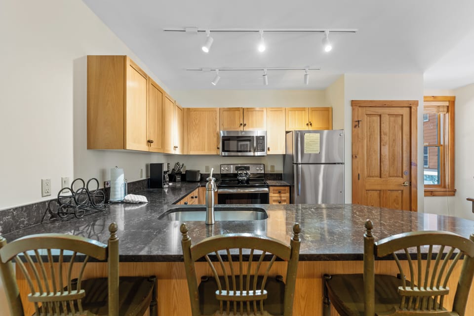 Your fully equipped kitchen features granite countertops, modern appliances, and a breakfast bar where you can enjoy morning coffee.