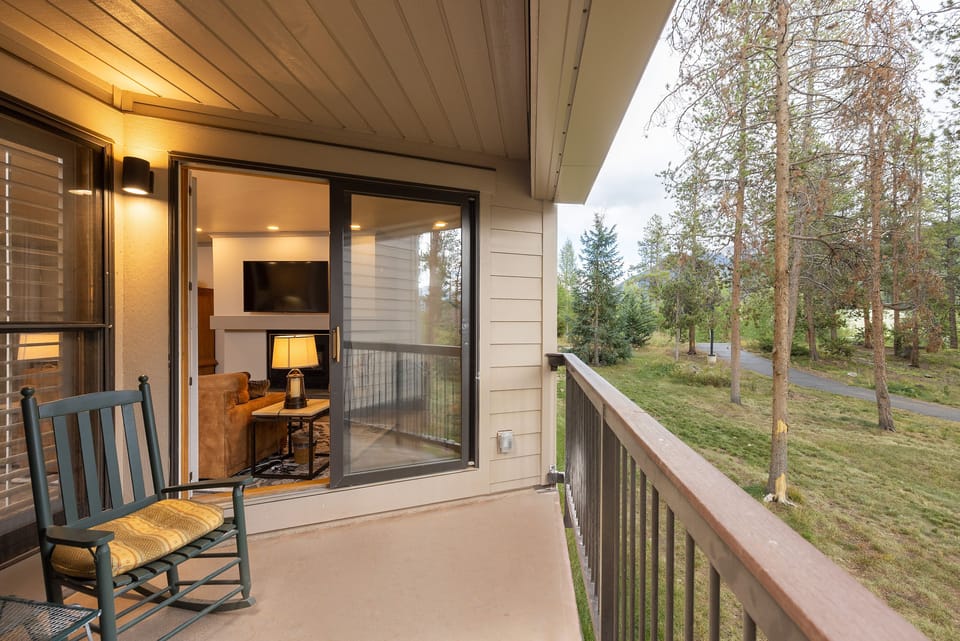 Unwind on your private balcony with forest views, where evening light filters through trees as you rock gently in your chair.