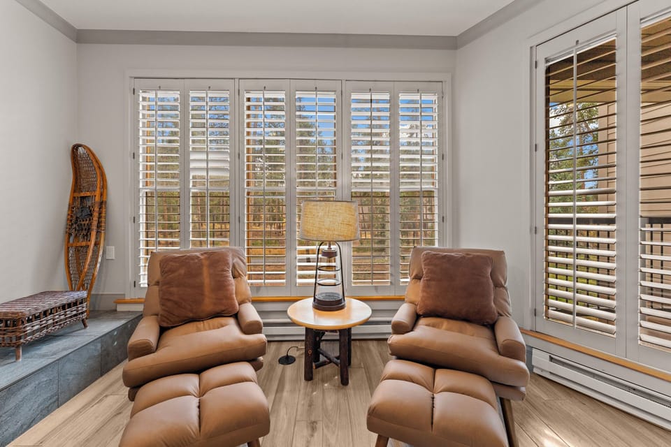 Unwind in your private reading nook with luxurious leather chairs and natural light streaming through elegant plantation shutters.
