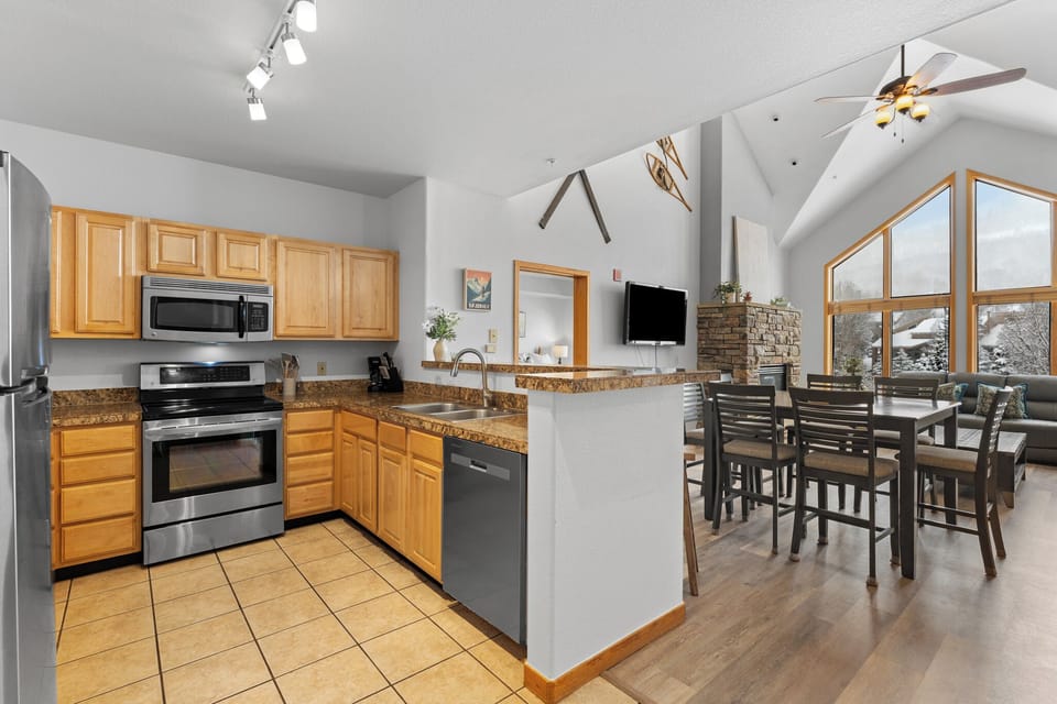 Your fully equipped kitchen flows into the bright dining and living areas where vaulted ceilings and mountain views create a welcoming space to relax together after adventures.