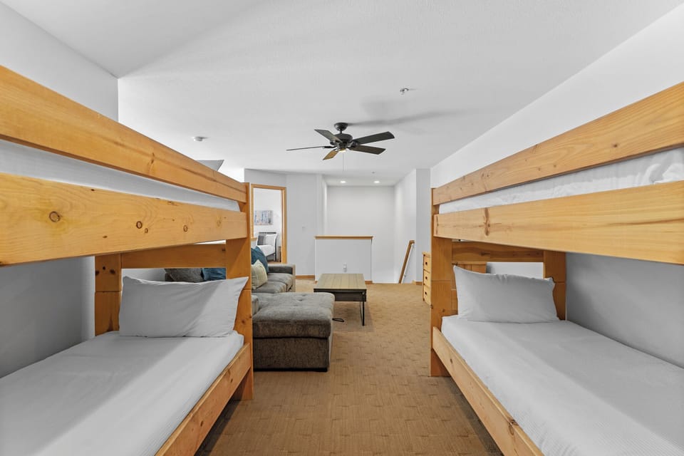 Gather your crew in this spacious bunk room, where sturdy wooden beds and cozy linens create a welcoming retreat for shared memories and restful nights.